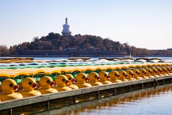Pekin, Çin 'deki Pekin Parkı' nda sarı ördek teknesi. Beihai Park 'taki beyaz kule.
