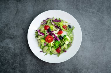 Bir tabak lezzetli ve sağlıklı sebze salatası. Gri beton zeminde bir tabak lezzetli ve sağlıklı sebze salatası..