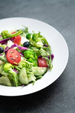 Bir tabak lezzetli ve sağlıklı sebze salatası. Gri beton zeminde bir tabak lezzetli ve sağlıklı sebze salatası..