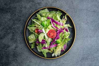 Bir tabak lezzetli yeşil sebze salatası. Gri beton zeminde lezzetli ve sağlıklı sebze salatası..