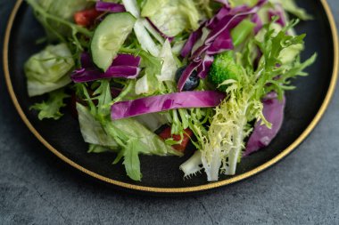 Bir tabak lezzetli yeşil sebze salatası. Gri beton zeminde lezzetli ve sağlıklı sebze salatası..