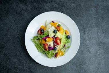 Bir tabak lezzetli ve sağlıklı sebze salatası. Gri beton zeminde bir tabak lezzetli ve sağlıklı sebze salatası..