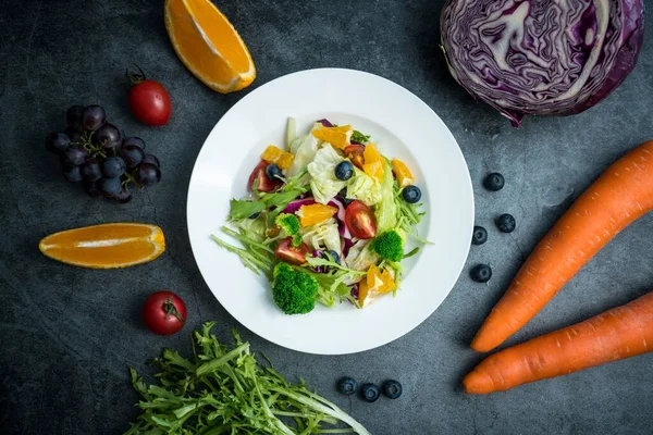 Bir tabak lezzetli ve sağlıklı sebze salatası. Gri beton zeminde bir tabak lezzetli ve sağlıklı sebze salatası..