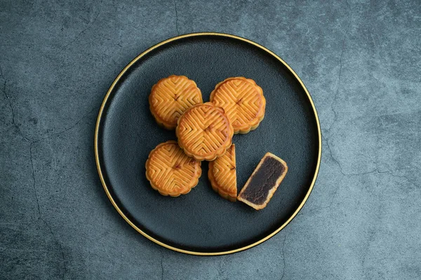 Sonbahar ortası festivali için ay çörekleri altın kaplamalı siyah bir tabağa konur.