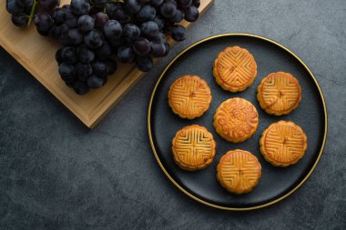 Sonbahar ortası festivali için bir tabak ay çöreği. Sonbahar ortası festivali için ay çörekleri altın kaplamalı siyah bir tabağa konuyor.