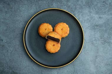 Sonbahar ortası festivali için ay çörekleri altın kaplamalı siyah bir tabağa konur.