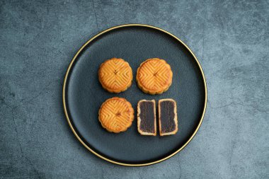 Sonbahar ortası festivali için ay çörekleri altın kaplamalı siyah bir tabağa konur.