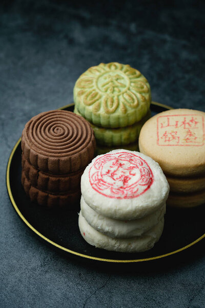 Delicious traditional Chinese pastry on a dark background. Chinese translation on pastry:Rose Cake with flowers, Hawthorn cake, Green tea crisp