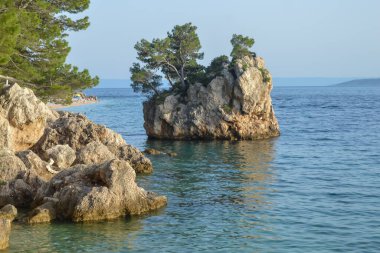 Hırvatistan 'ın Brela tatil beldesindeki Adriyatik Denizi plajı. Hırvatistan 'ın Dalmaçya kenti Makarska Riviera' nın Brela tatil beldesindeki Punta Rata plajındaki ada