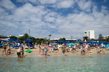 PROTARAS, CYPRUS - 16 Haziran 2018 'de Kıbrıs Rum Kesimi' nin Protaras kentinde güneşli bir günde yerel belediye plajı insanlarla dolup taşıyor. 