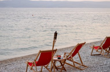 Hırvatistan 'ın Brela kentindeki Adriyatik Denizi' nin arka planında alevli plaj sandalyeleri