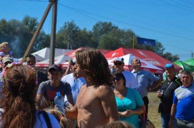 Velyki Sorochintsi, UKRAINE - 25 Ağustos 2017: Çocuk Ukrayna 'nın ulusal yıllık pazarı Sorochinska Yrmorka' da kırmızı kadın botlarını almak için tahta kaygan sütuna tırmanıyor