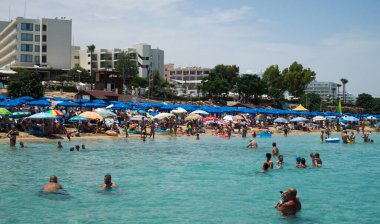 PROTARAS, CYPRUS - 16 Haziran 2018 'de Kıbrıs Rum Kesimi' nin Protaras kentinde güneşli bir günde yerel belediye plajı insanlarla dolup taşıyor. 