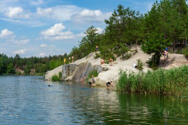 KOROSTYSHIV, UKRAINE - 21 Haziran 2020: Terk edilmiş Korostyshiv taş ocağı, derin mavi suları ve engebeli uçurumlarıyla dinlenme, balık tutma ve yüzme için manzaralı bir yer haline geldi..