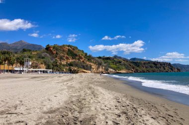 NERJA, İspanya - 22 Mart 2025: Işıldayan deniz ve büyüleyici şehrin muhteşem manzaraları, 22 Mart 2025 tarihinde İspanya 'nın Nerja kentinde nefes kesen kıyı manzaraları ve pitoresk bir atmosfer sunuyor.