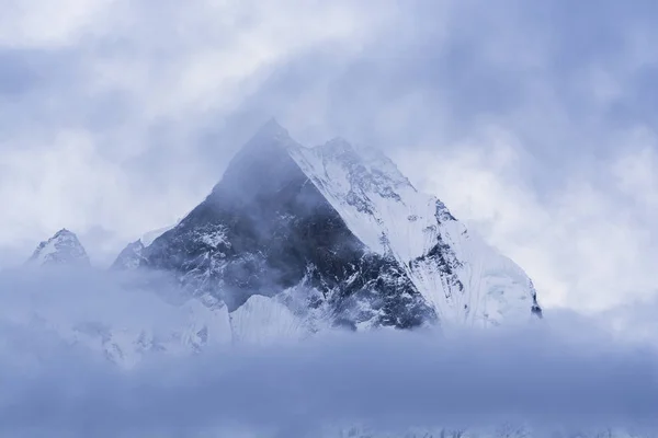 Nepal'deki dağ zirvesi. Sis içinde kar ile Kaya dağı
