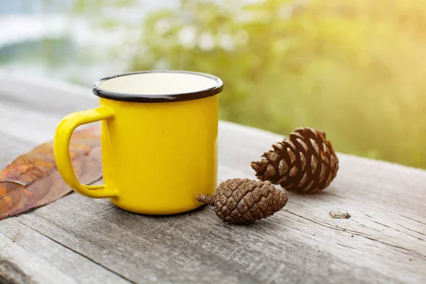 Yellow mug on wooden table with nature background in the morning