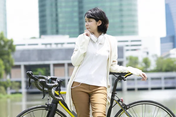 Feliz mulher asiática com bicicleta perto do lago — Fotografia de Stock
