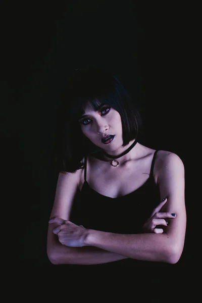 Weird woman with dark tone makeup on black background, portrait