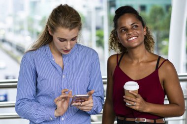 Beyaz kadın cep telefonu kullanarak ve gülümseyen siyah woma konuşuyor