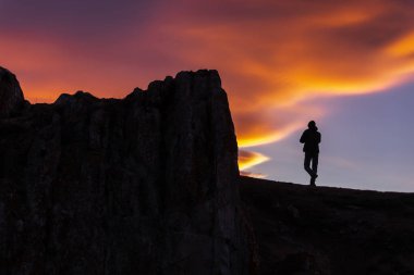 Alacakaranlıkta uçurumda kişinin siluet fotoğraf