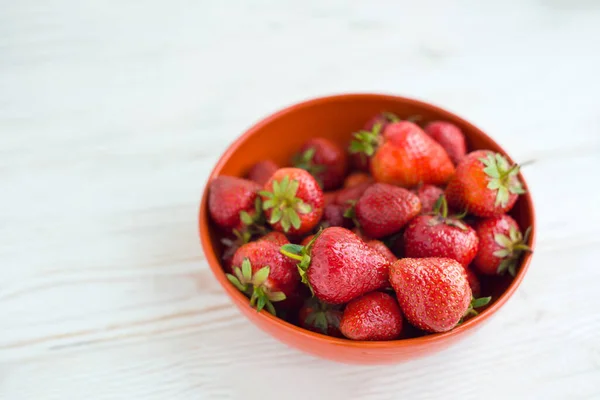 在白色木制桌子的背景上 用橙色碗盘中的新鲜成熟美味草莓做特写 抗氧化营养 健康的有机食品概念 复制空间 平躺在床上天亮了 — 图库照片