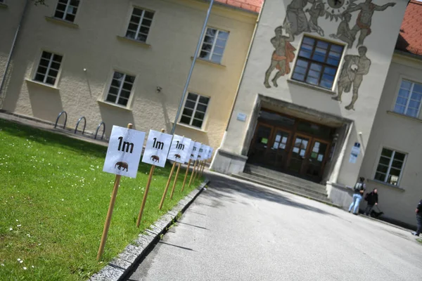 Corona krizi - Wels şehrinde bir okulun önünde (Yukarı Avusturya, Avusturya, Avrupa), işaretler bir metre belirtilmiş uzaklığı gösterir
