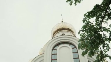 Bulutlu gökyüzüne karşı Beyaz Kilise ve yeşil ağaç dalları