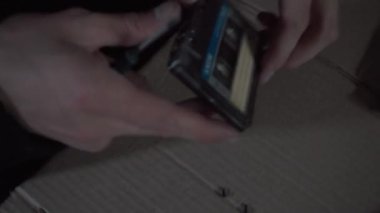 Bir adam ses kasetini tamir ediyor.