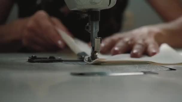Une couturière coud sur une machine à coudre ourle un tissu avec un joli motif pour le linge de lit 