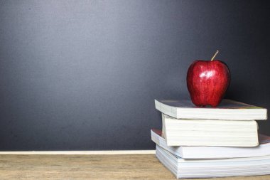 Kırmızı elma yazı tahtası (tebeşir tahtası) arka plan olarak bir kitapla ahşap masa üzerinde üzerinde. Eğitim kavramı.