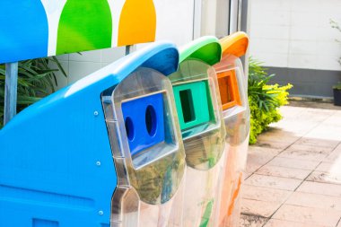 Parkta geri dönüşüm sembolü ile sarı, yeşil, mavi geri dönüşüm kutularını kapatmak.