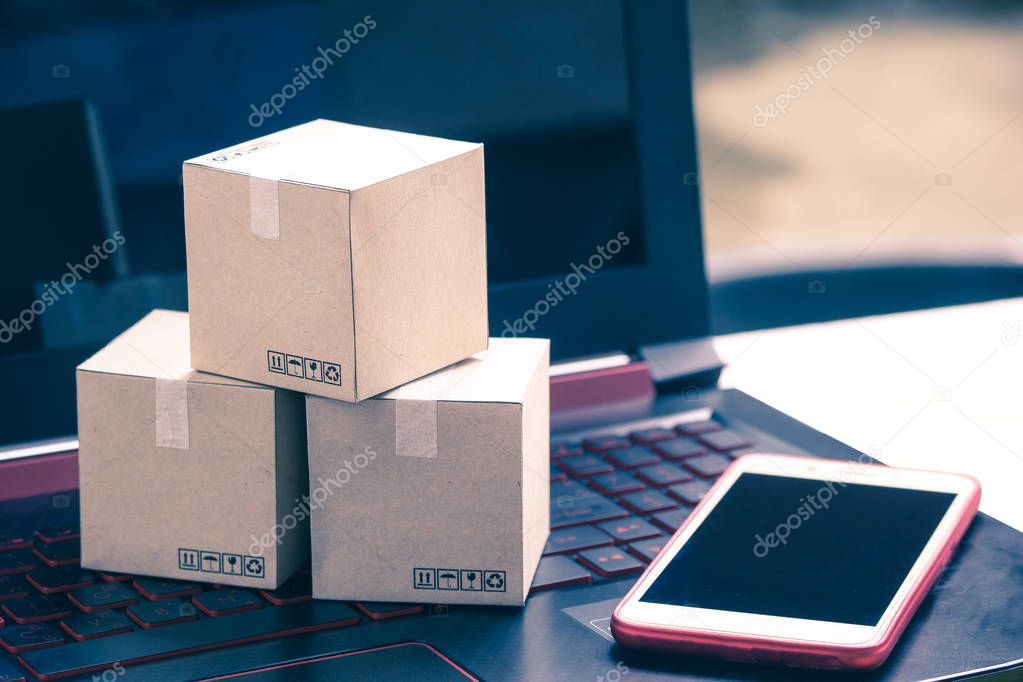 Online shopping concept e-commerce delivery buying service. square cartons shopping on laptop keyboard, showing customer order via the internet and smartphone.