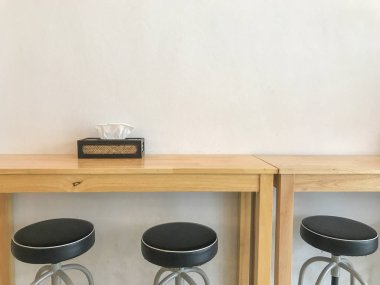 Uzun oturma masa ve sandalyeler kafede peçete ve kutusu ile. Beyaz çimento duvar arka plan kopya alanı ile. Akşam veya öğleden sonra ara yer.