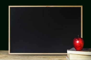 Siyah kara tahta dokulu arka plan için ahşap masa üzerine yığılmış kitap üzerinde kırmızı elma ve temiz. Siyah okul kavramı için. Reklam, satış. eğitim kavramı.