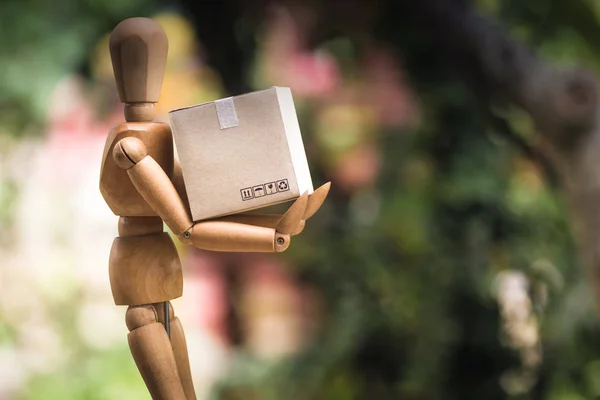 Delivery concept : Wooden mannequin holding paper carton ready delivery to customers from online order. Transport shopping concept. Conceptual transport delivery service for customers.