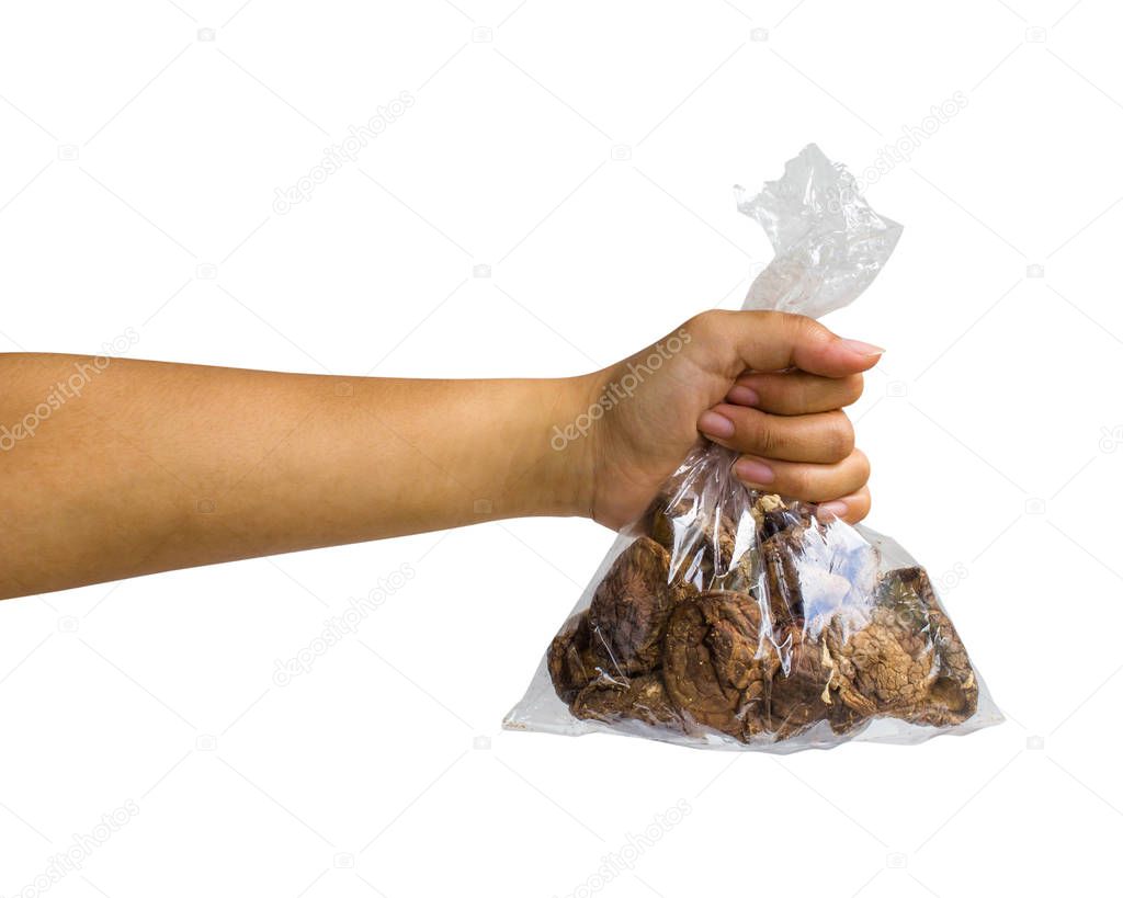 Hand isolated : A cropped female hand holding black Dried mushrooms in transparent plastic bag on white background include clipping path Easy to use for your work. 