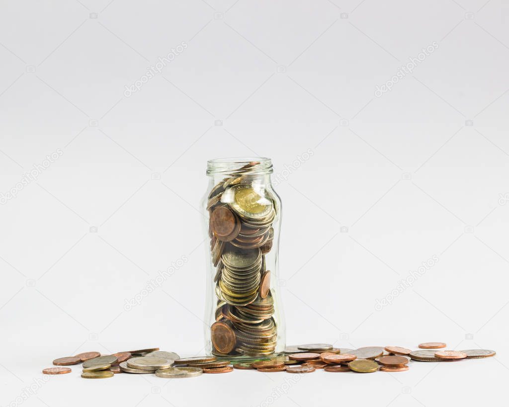Savings, Investment growing money concept : A full coins in a clear glass jar with many coin on white background.