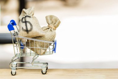 Daha fazla alışveriş yapmak için yapmak para için alışveriş kavramı: bize dolar paran kopya alanı ile ahşap tabloda küçük alışveriş arabası. Web alışveriş banner, reklam, tasarım pop için arka plan.