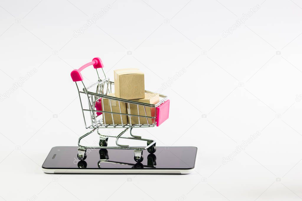 Online marketplace delivery, shopping at home or every where is easy concept : Paper cartons put in a shopping cart on tablet or smartphone against white background. Demonstrate fast order delivery.