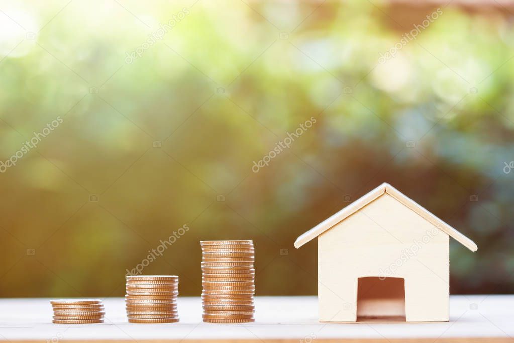 Property investment,  home loan, house mortgage, resident financial concept : Stacking coins in 1 to 3 step with small house on table over green nature background. Demonstrate growth of real estate.