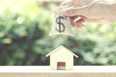 Kaydetme para, konut kredisi, mortgage, gayrimenkul yatırım için gelecekteki kavramı: paran küçük konut ev ve yeşil doğa arka plan ile koyarak bir adam el. Sürdürülebilir yatırım.