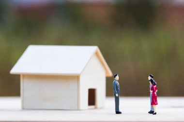 Anasayfa pazarlık, gayrimenkul, kredi, ev borç veren ters ipotek kavramı: üç minyatür pazarlık açık küçük ikamet ahşap masa ve bulanık yeşil doğa arka plan olarak. Ticaret evi.