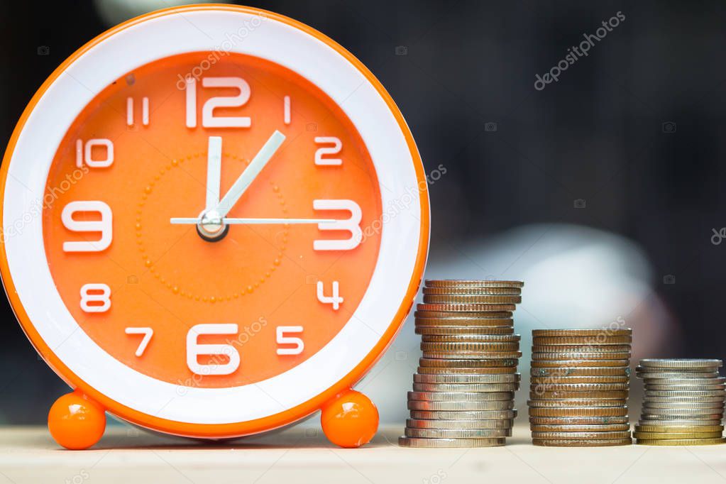 Money savings, Investment, time and money growing concept : Stacking growing coins, Moneybags and orange clock on wooden table. Saves money for the future. Time investment use money for work.