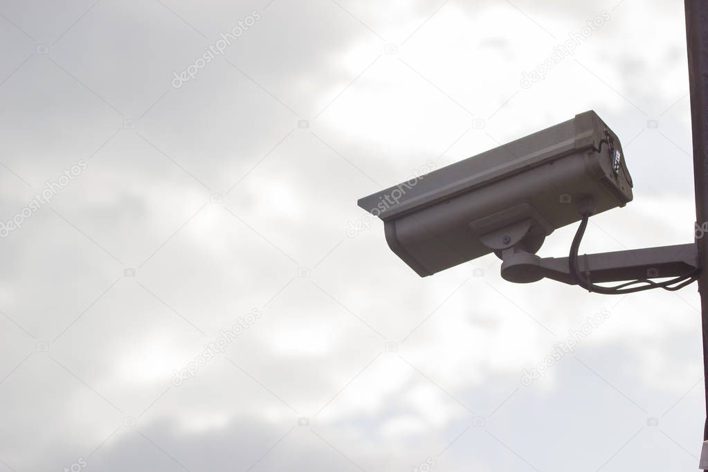 CCTV security video camera protect on the clouds and sky background.