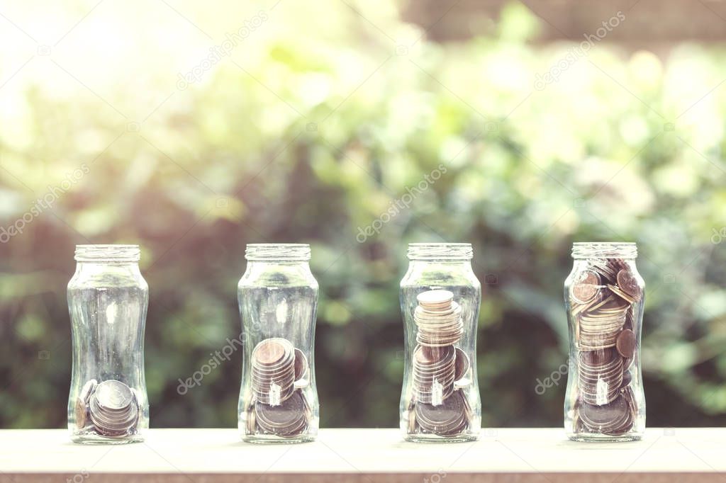 Money savings and investment concept : Stacked coins in 4 step growing on wooden table with nature background. Depicts sustainable investment and environmentally friendly in the future.
