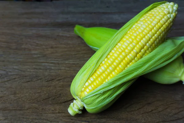 Taze tatlı mısır koçanı yaprakları ahşap masa arka plan üzerinde ile kapatmak.