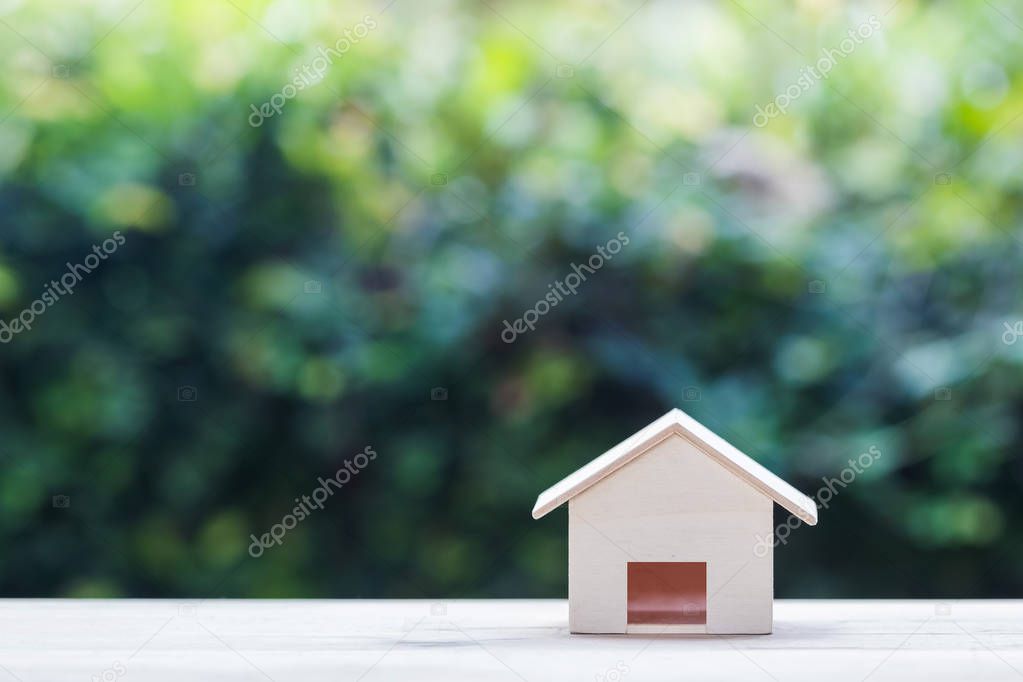 Home loan. Mortgage concepts Small wooden resident craft on table with green nature background.