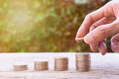 Para tasarruf, yatırım, gelecek, mali servet yönetimi kavramı için para kazanmak. Yığın 4 adım büyüyen paraları. Sikke üzerinde yığılmış paraları tutan bir adam el. Yeşil Doğa arka plan.