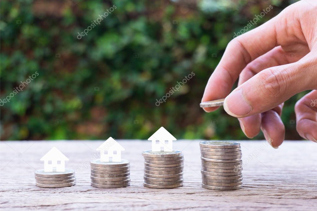 Property investment, home loan, house mortgage, resident financial concept. Stacking coins in 1 to 4 step with small house papercut on coin with nature background. Demonstrate growth of real estate.